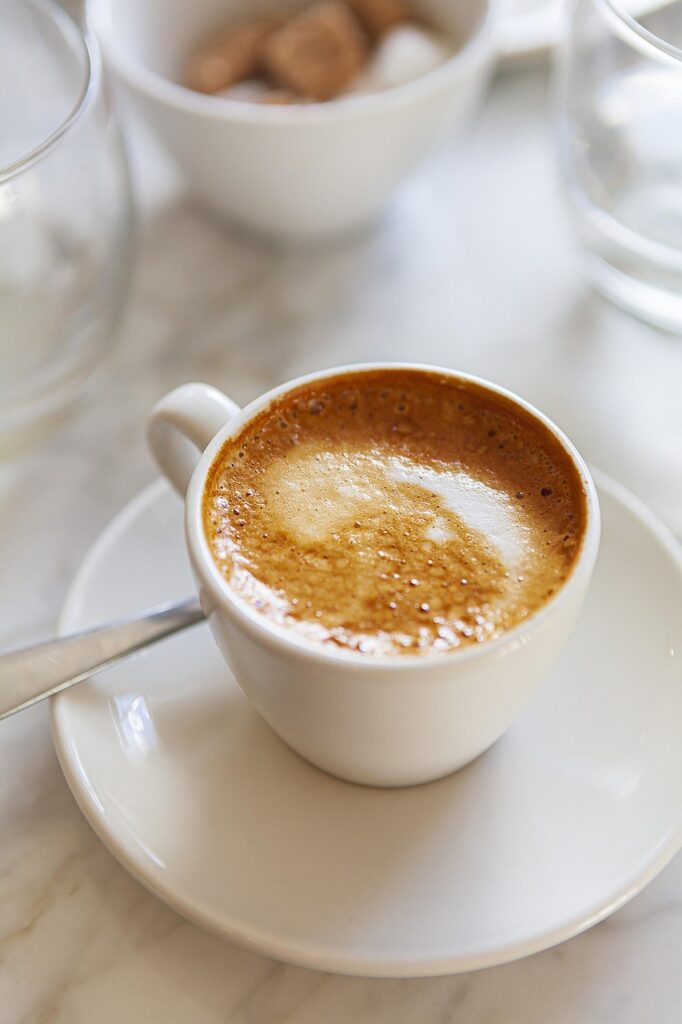 Picture of a coffee mug sitting on a table with a spoon next to it. 